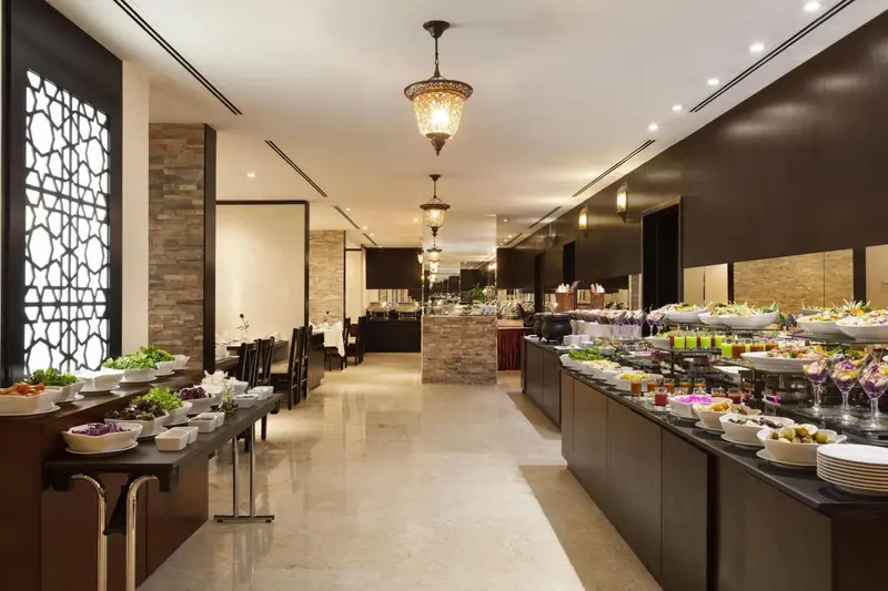 Un buffet de salades et de plats froids est présenté dans une salle lumineuse et décorée.
