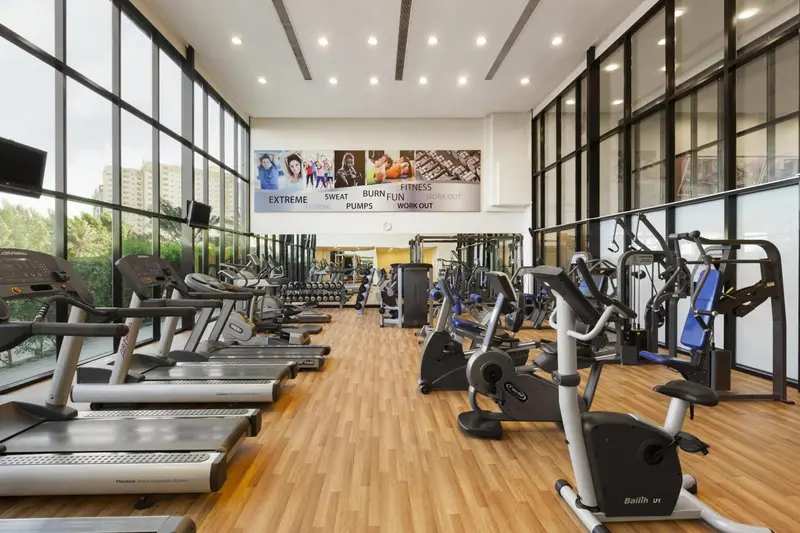 Une salle de sport lumineuse avec des équipements de fitness alignés sur un parquet clair.
