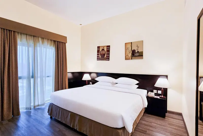 Une chambre lumineuse avec un grand lit et des rideaux décoratifs.