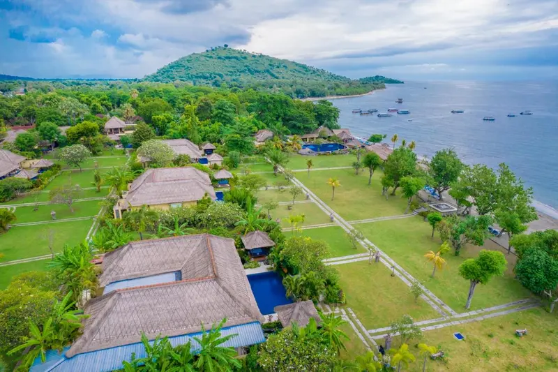 Vue aérienne d'un complexe hôtelier tropical avec des bungalows et des piscines.