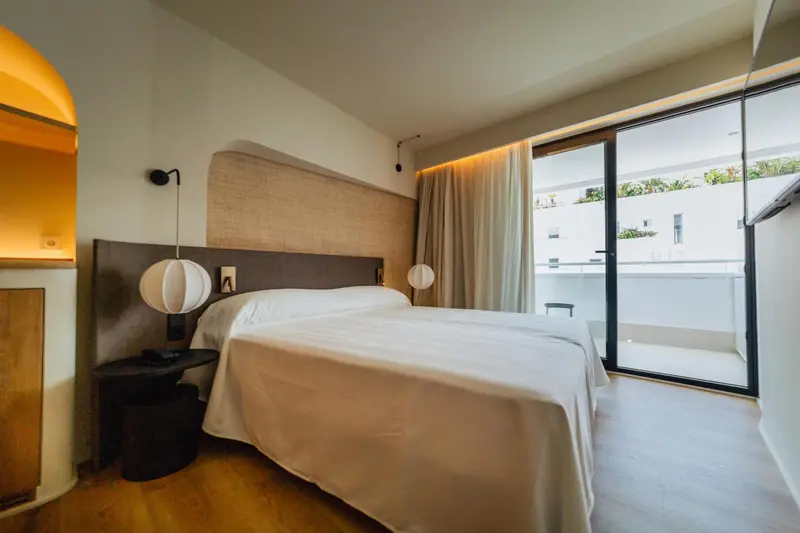 Une chambre lumineuse avec un grand lit et un accès à une terrasse.