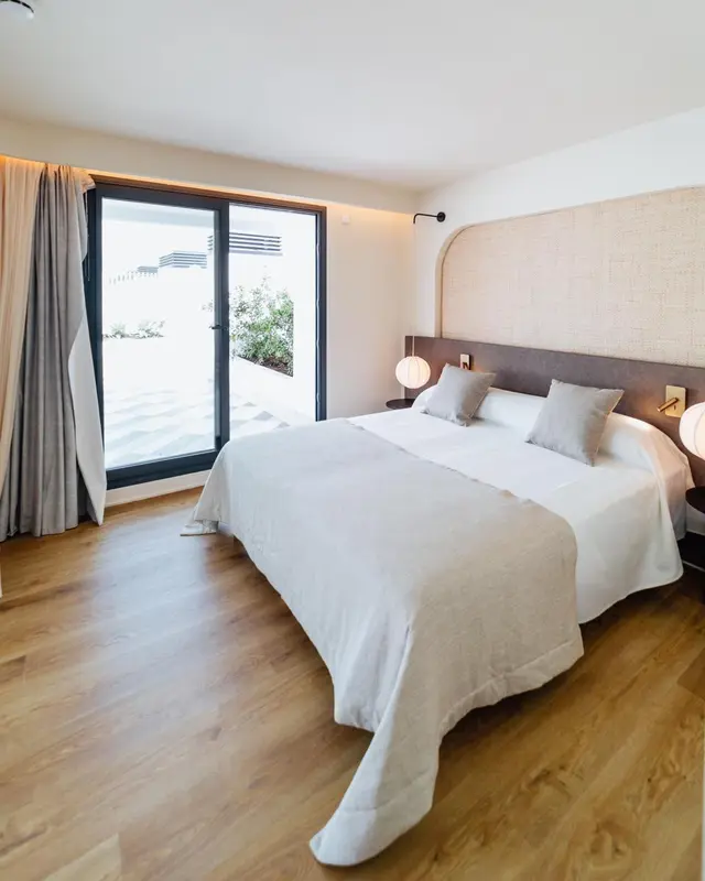 Une chambre lumineuse avec un grand lit et un accès à une terrasse.