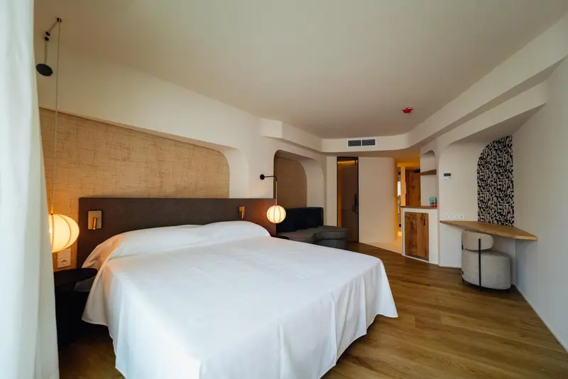 Une chambre lumineuse avec un grand lit recouvert d'une couette blanche.