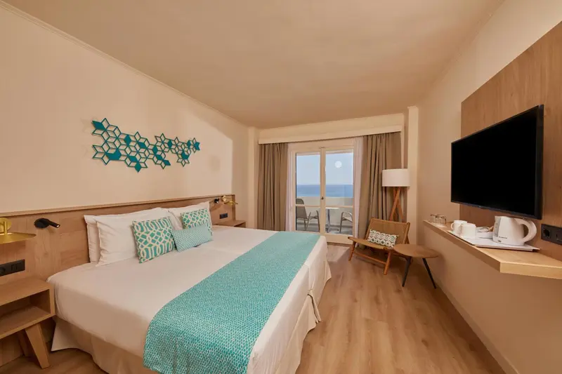 Chambre lumineuse avec un grand lit et une vue sur la mer.