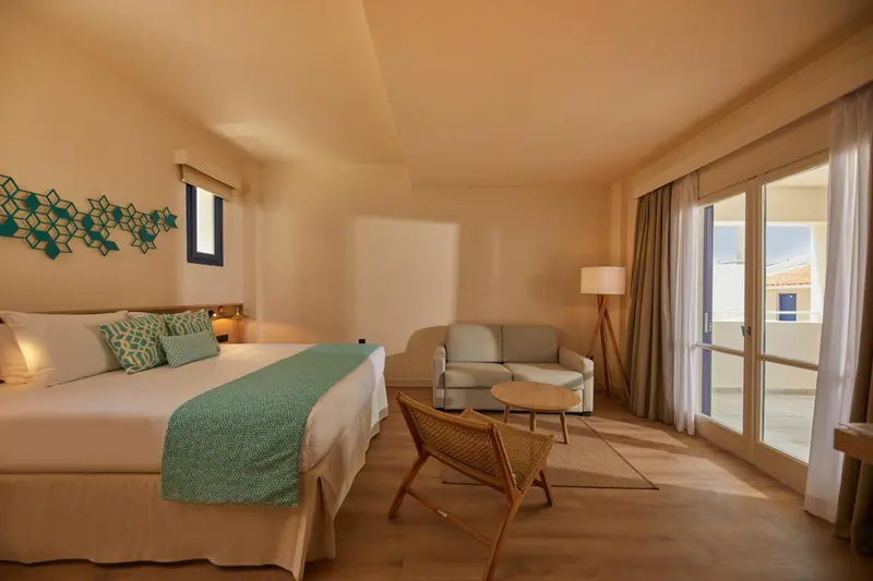 Une chambre lumineuse avec un lit et un coin salon.