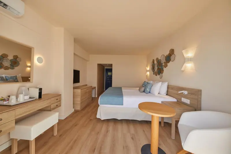 Une chambre lumineuse avec un lit double et un coin repos.