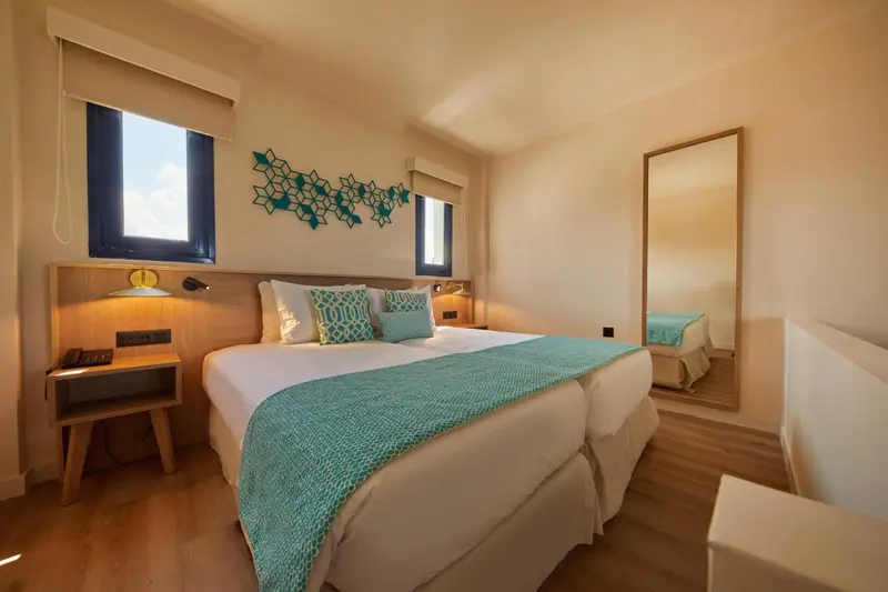 Une chambre lumineuse avec un grand lit et un miroir.