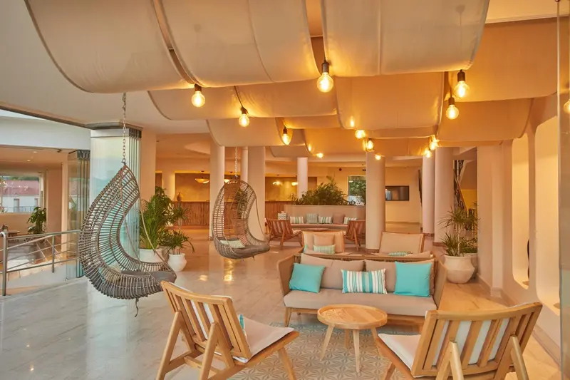 Espace de détente intérieur avec canapés et fauteuils sous une structure lumineuse.