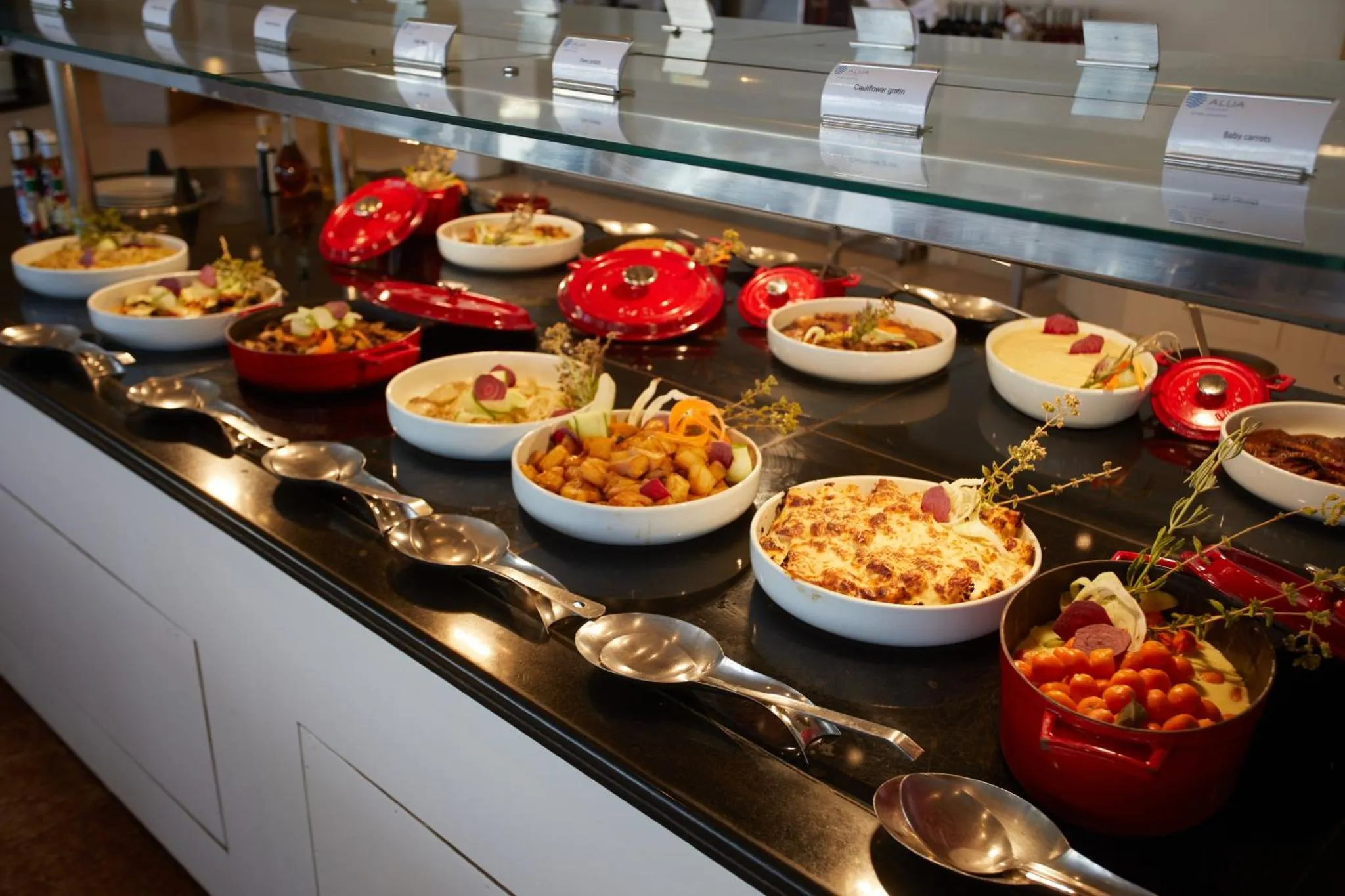 Un buffet propose une variété de plats colorés dans des récipients en céramique.