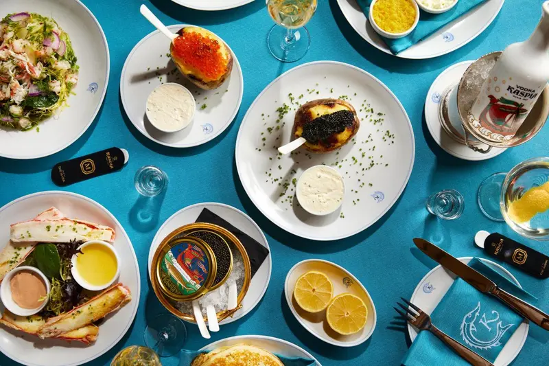 Assortiment de mets raffinés présentés sur une table recouverte d'une nappe bleue.
