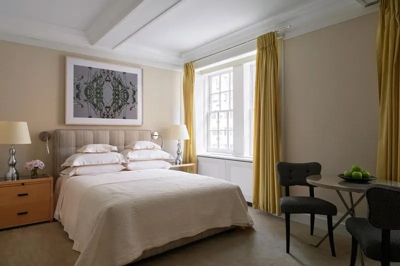 Une chambre lumineuse avec un grand lit et un coin repas près de la fenêtre.