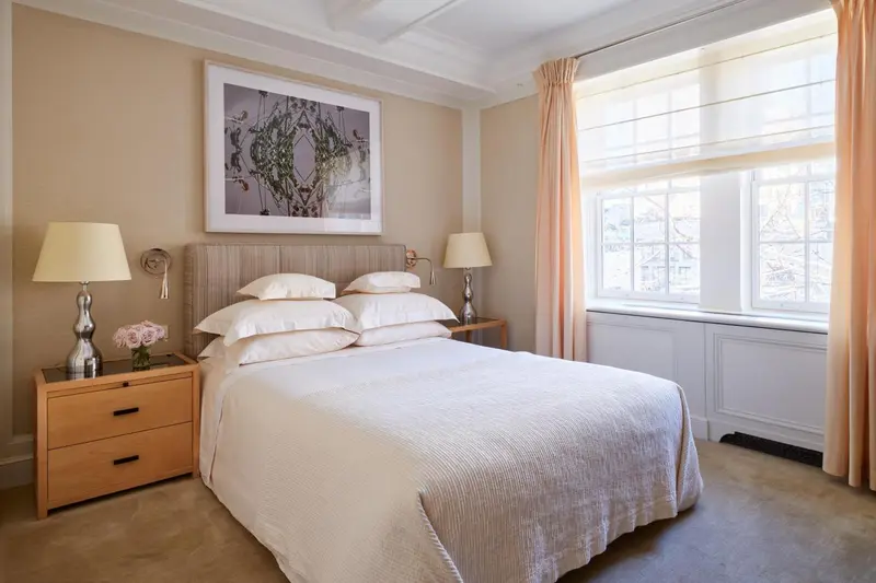 Une chambre lumineuse avec un grand lit recouvert d'une courtepointe blanche et de coussins.