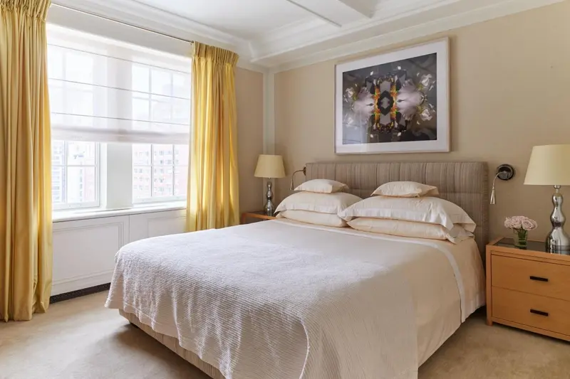 Une chambre lumineuse avec un grand lit et des rideaux jaunes.