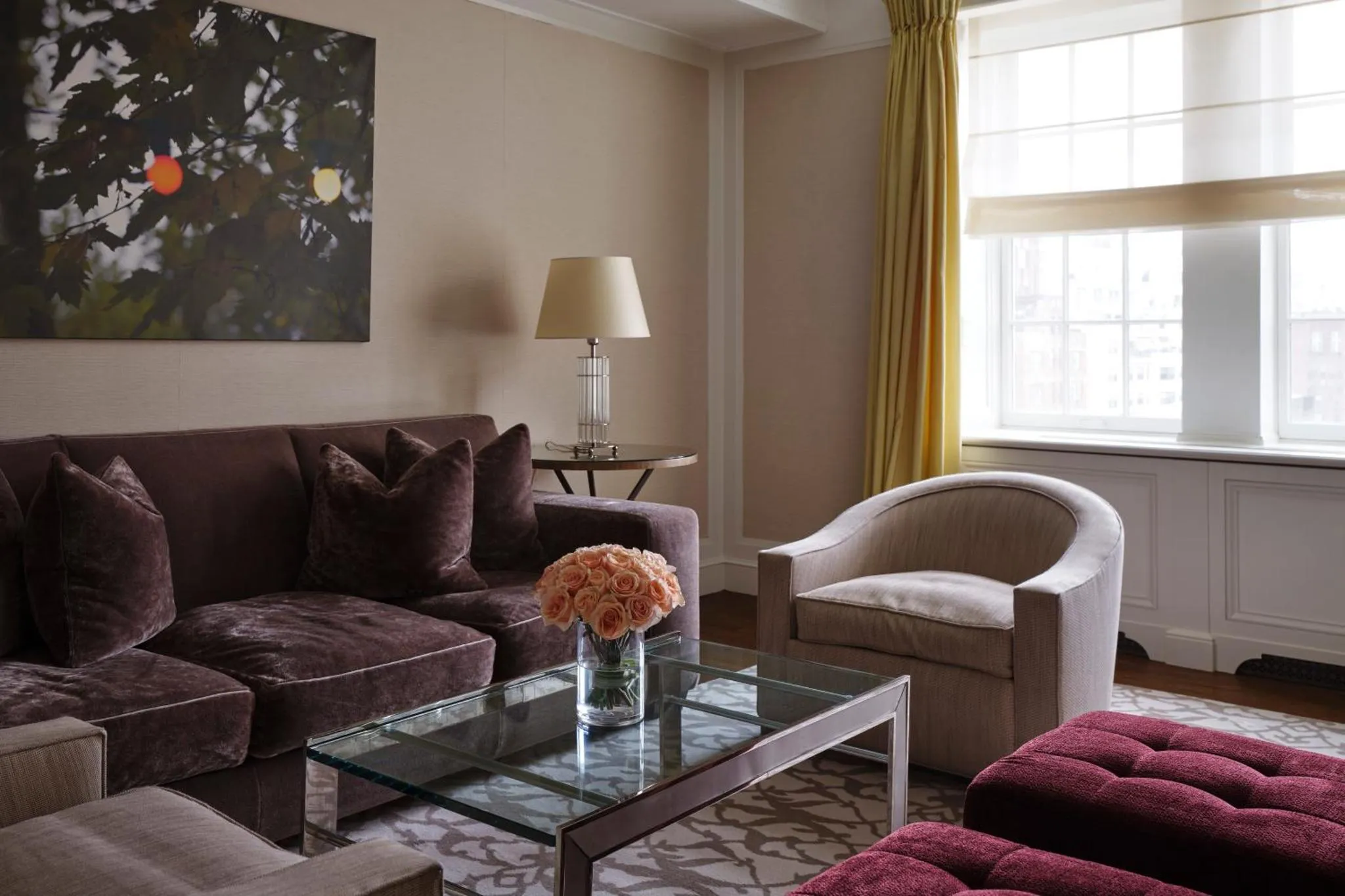 Un salon confortable avec canapés violets, fauteuil beige et table basse en verre.