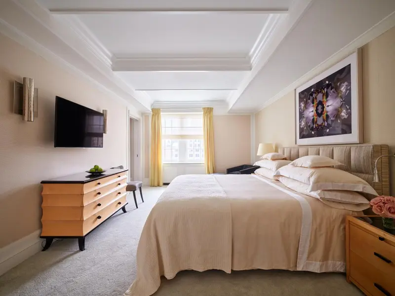 Une chambre lumineuse avec un grand lit et une commode en bois.