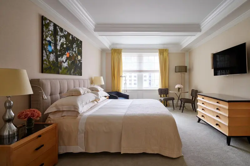 Une chambre lumineuse avec un grand lit et un coin salon près de la fenêtre.