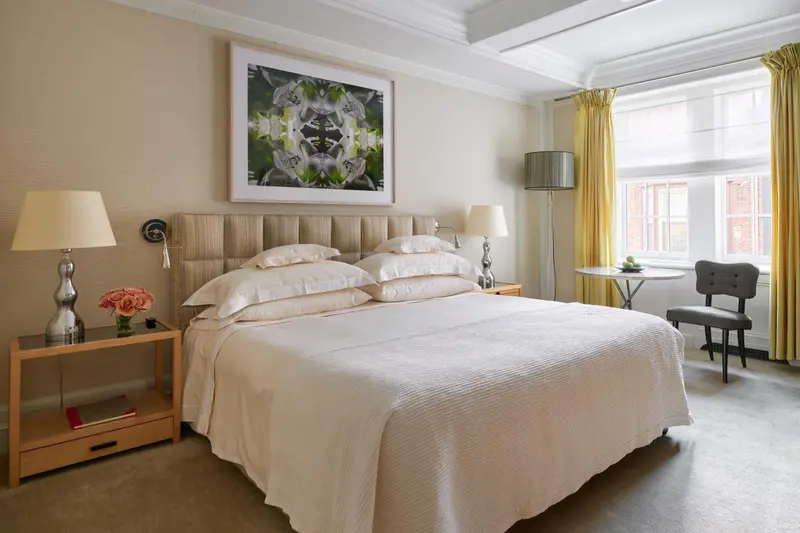 Une chambre lumineuse avec un grand lit recouvert d'une courtepointe blanche et de coussins.