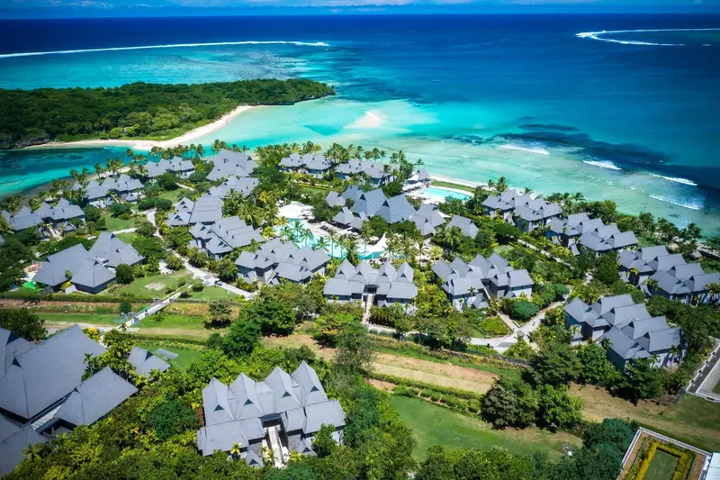 Vue aérienne d'un complexe hôtelier bordant une plage de sable blanc et une eau turquoise.
