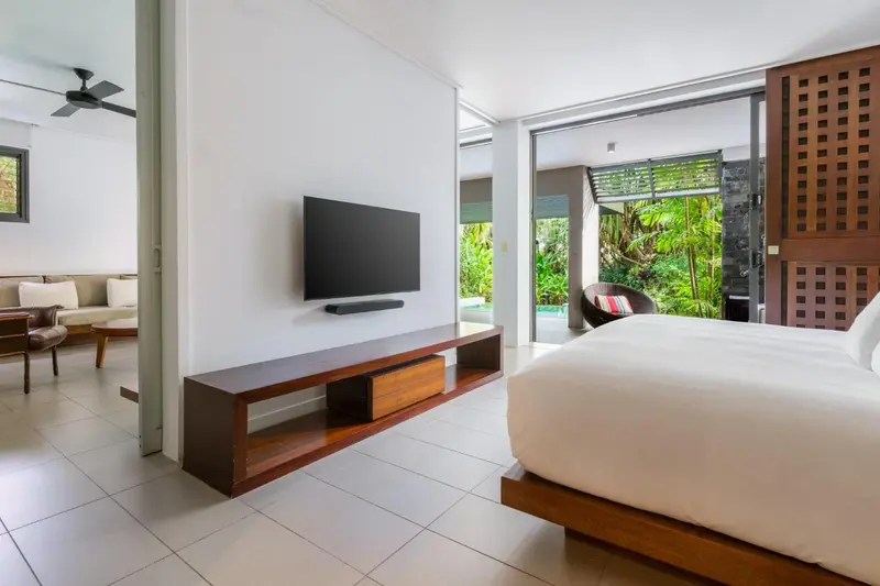 Une chambre lumineuse s'ouvre sur une terrasse avec une piscine.