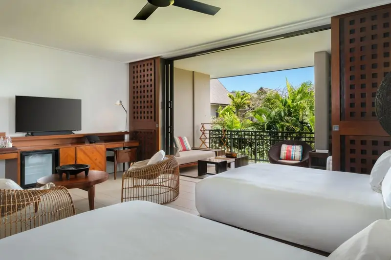 Une chambre lumineuse s'ouvre sur une terrasse avec des fauteuils.