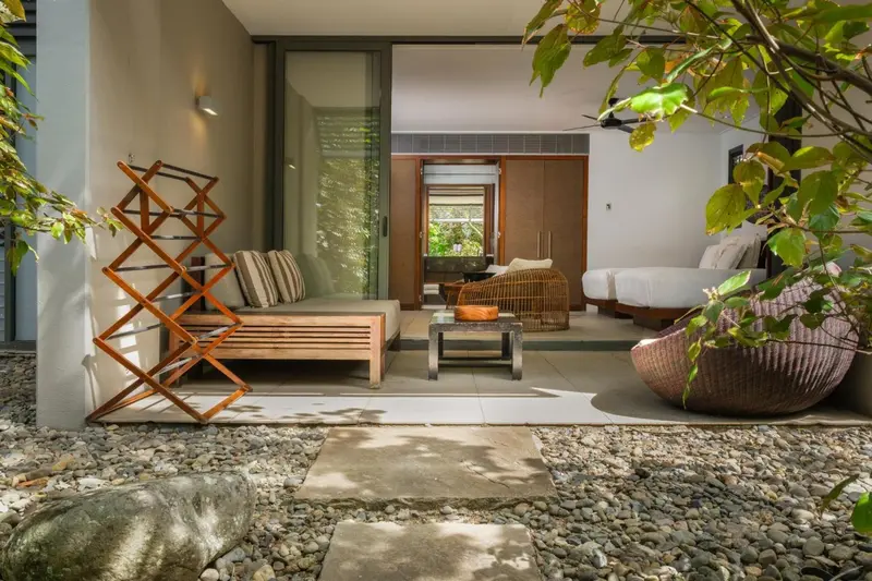 Espace extérieur aménagé avec mobilier en bois et végétation luxuriante.