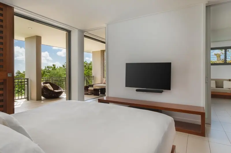 Une chambre lumineuse s'ouvre sur une terrasse avec mobilier d'extérieur.