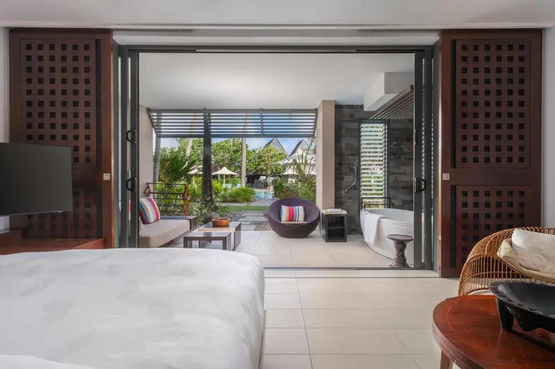 Une chambre lumineuse s'ouvre sur une terrasse avec salon et bain extérieur.