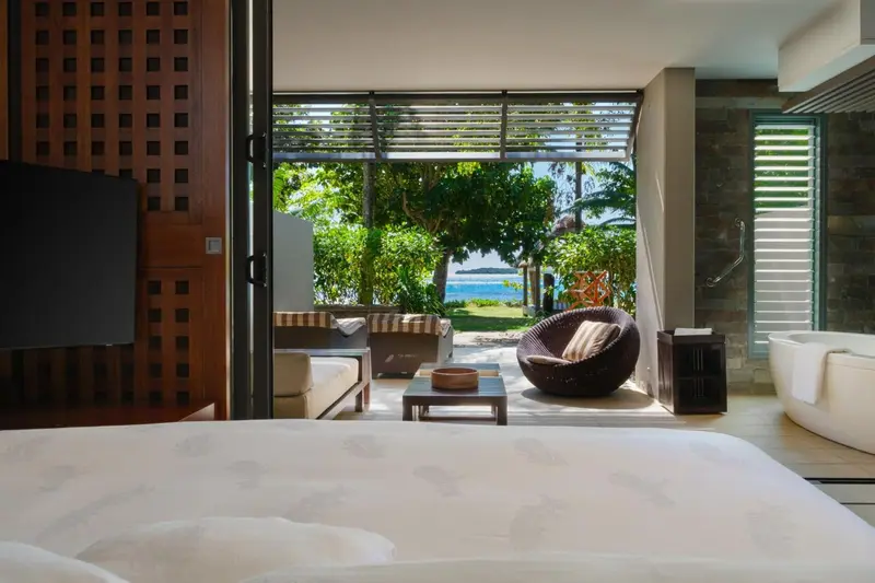 Espace de vie intérieur lumineux donnant sur une végétation luxuriante et la mer.