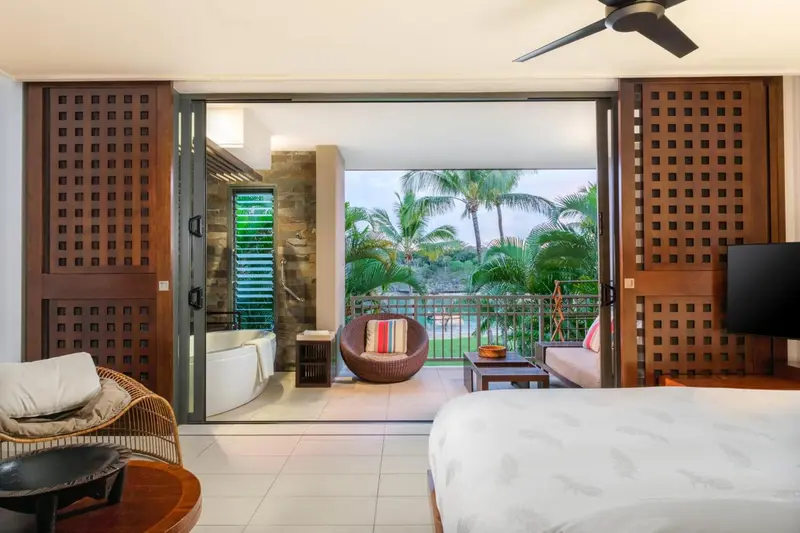 Une chambre s'ouvre sur une terrasse avec vue sur la végétation tropicale.