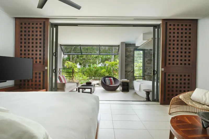 Une chambre lumineuse s'ouvre sur une terrasse avec mobilier d'extérieur.