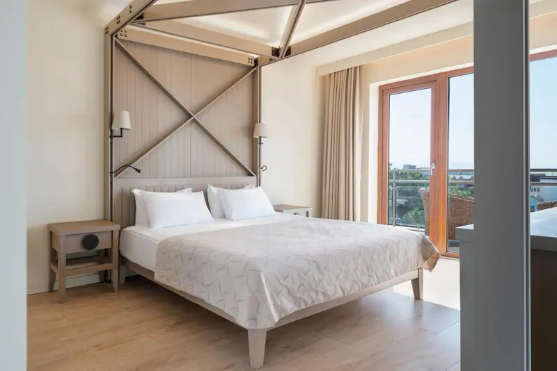 Une chambre lumineuse avec un grand lit et une vue sur l'extérieur.