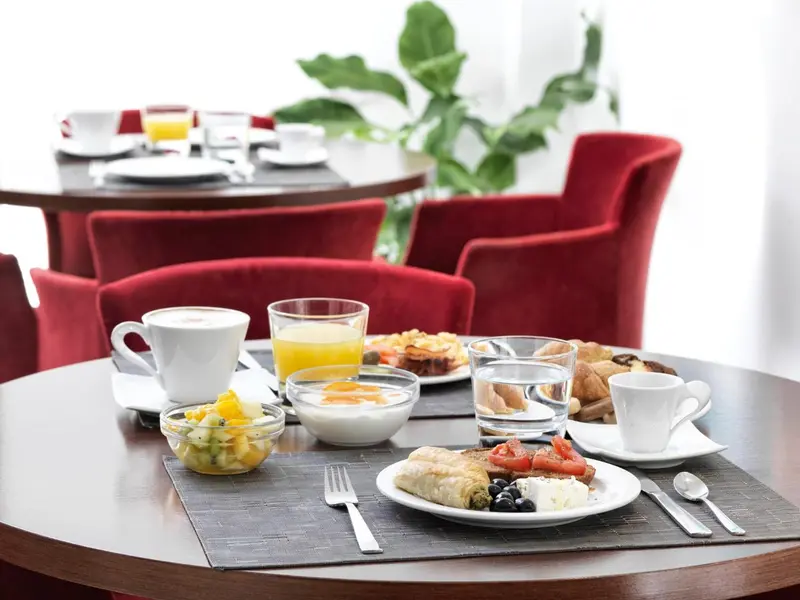 Une table ronde est dressée pour le petit-déjeuner avec des viennoiseries et des fruits.