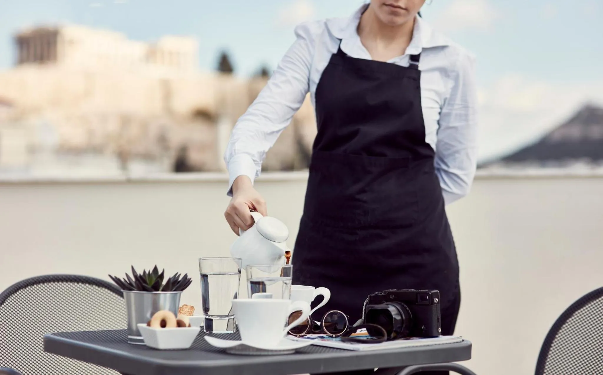 Une personne sert une boisson à table en extérieur.