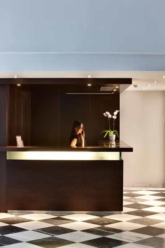 Une réception d'hôtel avec une employée et une décoration florale.