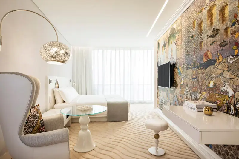 Une chambre lumineuse avec un lit et un fauteuil design.
