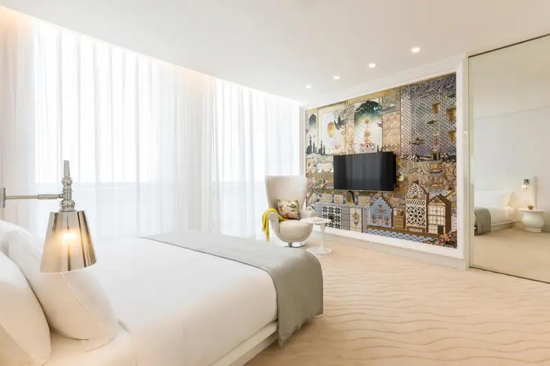 Chambre lumineuse avec un grand lit et un fauteuil design.