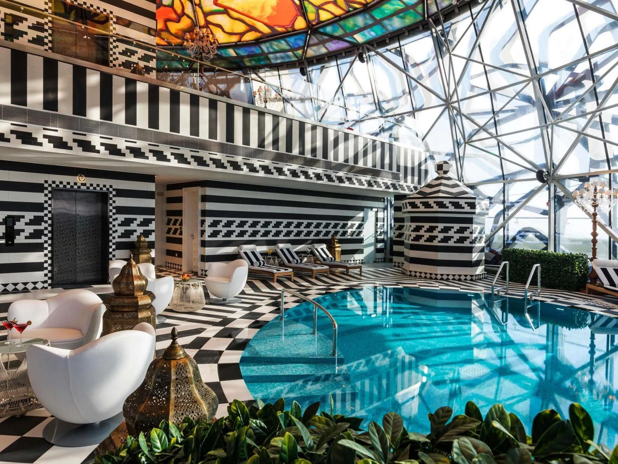 Espace de détente intérieur avec piscine et mobilier blanc et noir.
