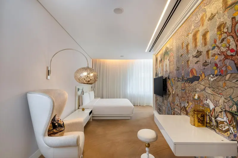 Une chambre lumineuse avec un fauteuil et un bureau.