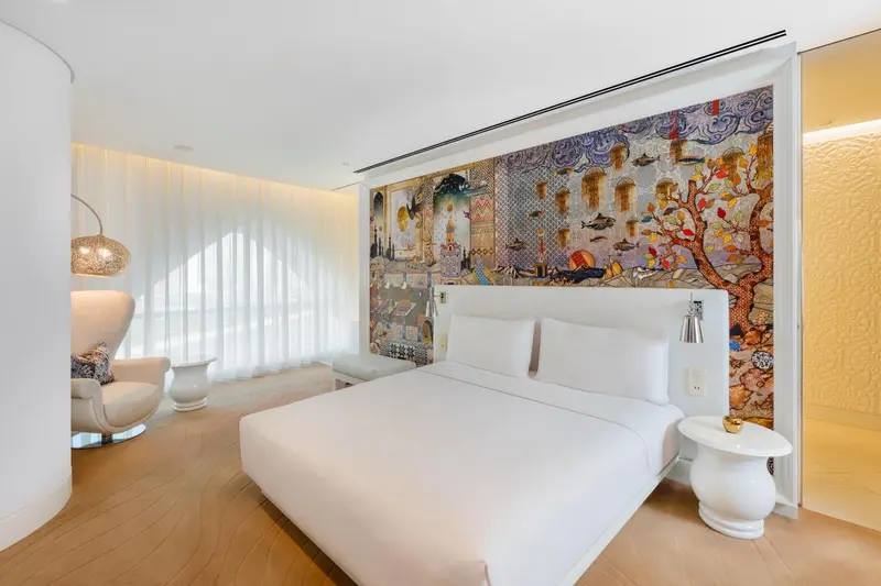 Une chambre lumineuse avec un grand lit et un mur décoratif.