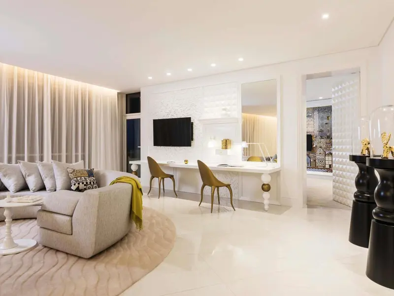 Un salon clair avec canapé, fauteuils et bureau.