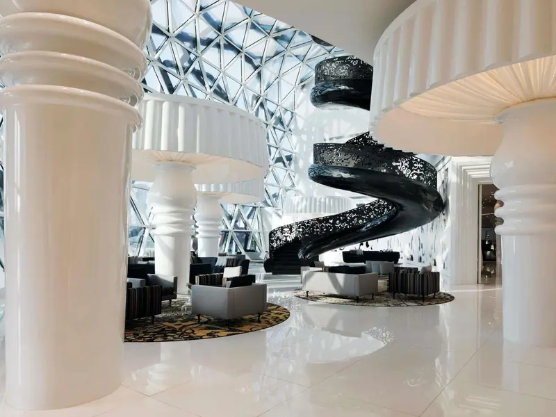 Un hall d'accueil lumineux avec un escalier en colimaçon noir.