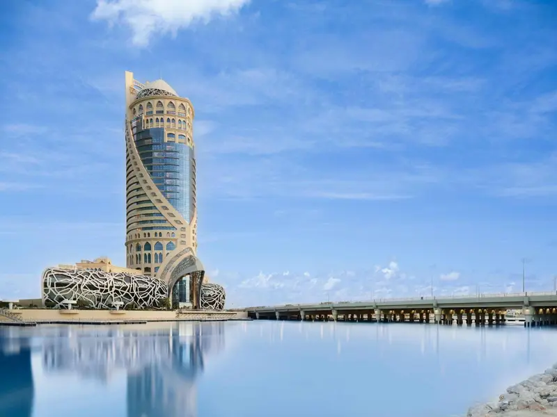 Bâtiment moderne au bord de l'eau sous un ciel bleu nuageux.