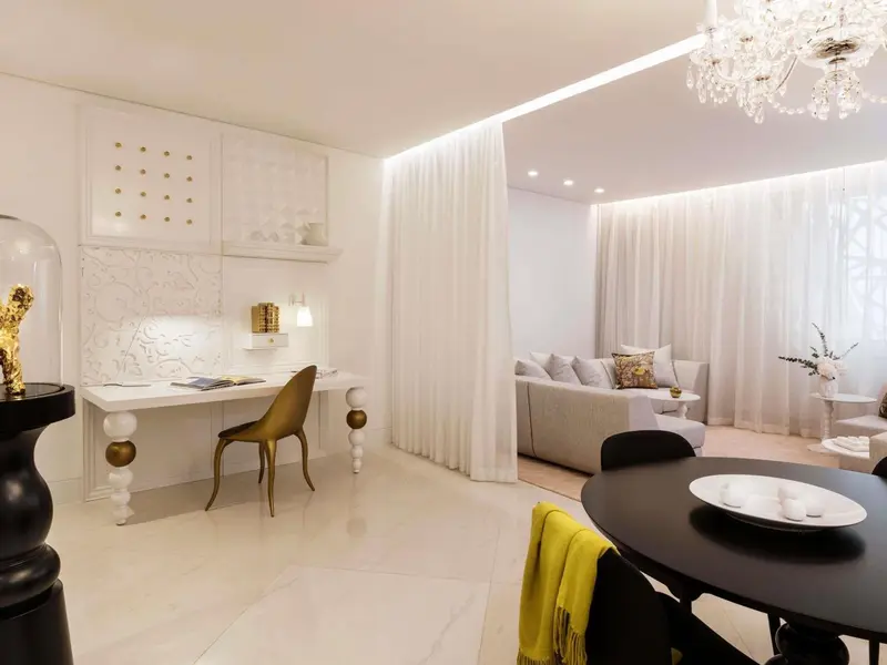 Une pièce lumineuse avec un bureau doré et un espace détente avec canapé et table basse.
