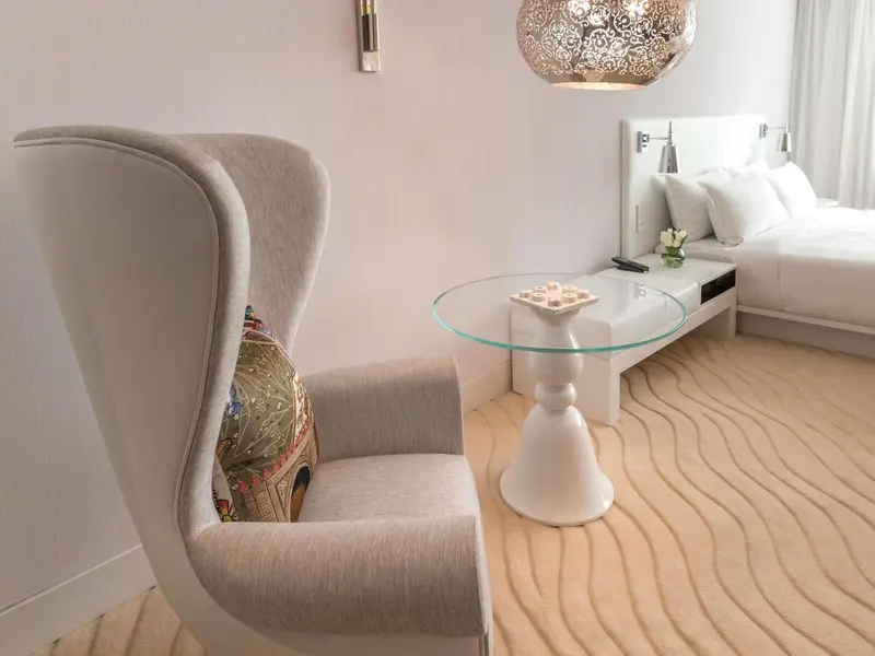 Une chaise confortable se trouve près d'un lit dans une chambre lumineuse.