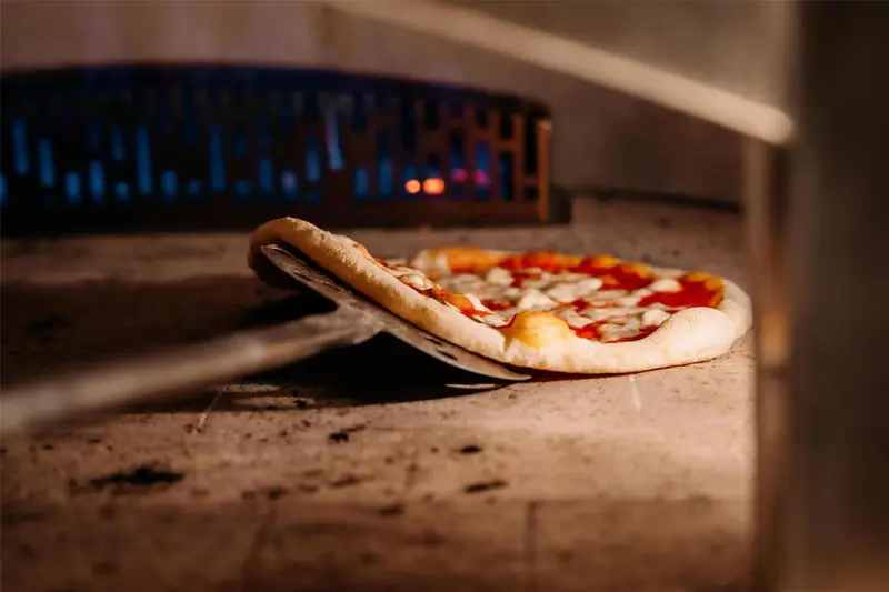 Une pizza est cuite dans un four à bois.