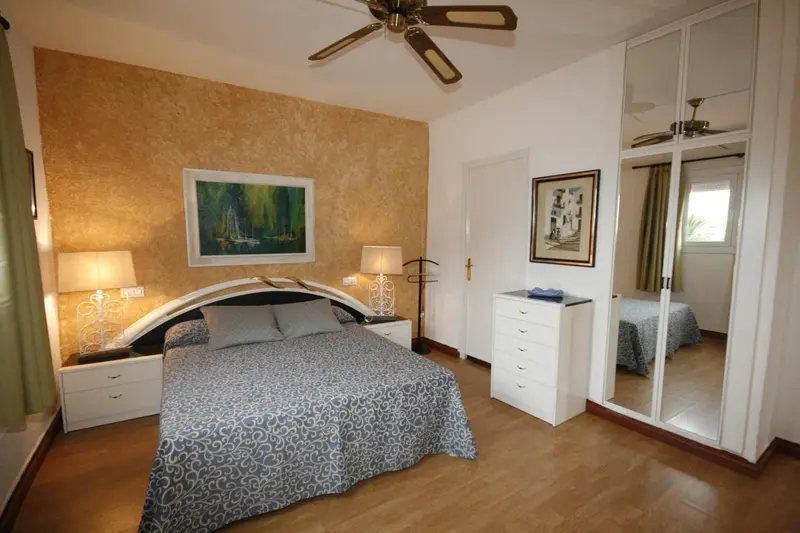 Une chambre à coucher lumineuse avec un grand lit et des meubles blancs.
