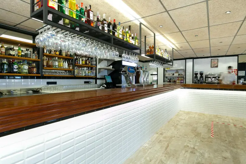 Un comptoir de bar en bois avec des bouteilles et des verres alignés.