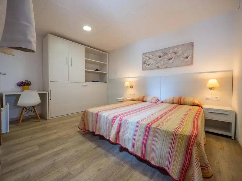 Une chambre lumineuse avec un lit double et un bureau.