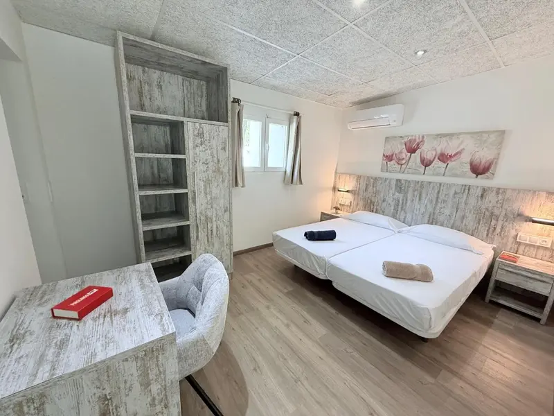 Une chambre lumineuse avec un lit double et un coin lecture.
