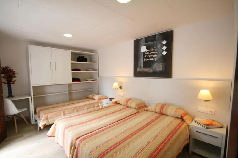 Une chambre avec deux lits simples et un bureau.